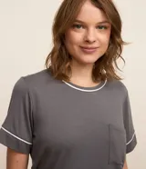 Conjunto de pijama corto compuesto por una remera gris de manga corta con bolsillo en el pecho y un short con estampado de cuadros blancos y grises.