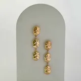 Aros colgantes dorados con tres piezas irregulares con textura martillada unidas por pequeñas argollas.