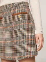 Minifalda de tweed a cuadros en tonos beige, marrón, negro, rojo y azul. Tiene dos bolsillos delanteros de parche con botones dorados con el logo de la marca.