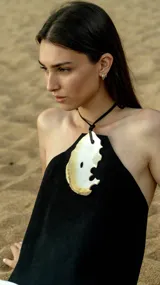 Top negro de cuero con corte irregular y aplique de nácar.