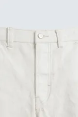 Bermuda de denim color blanco roto con efecto encerado, corte amplio (baggy fit) y cinco bolsillos. Presenta cierre frontal con cremallera y botón.