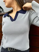 Remera de manga larga blanca con cuello polo negro.