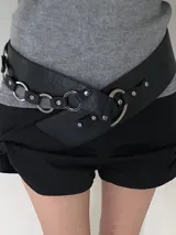 Cinturón ancho de cuero sintético negro con cadena de eslabones plateados y detalle de tachas.