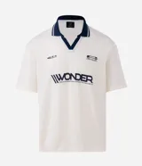 Remera de manga corta con cuello polo contrastante en azul marino y abertura en V. El cuerpo de la prenda es color crema y lleva un estampado frontal con la palabra "WONDER".