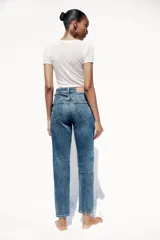 Pantalón de jean gris oscuro, de corte mom fit, tiro alto y largo tobillero. Cuenta con cinco bolsillos, cierre frontal con cremallera y botón.