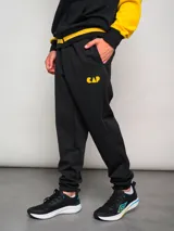 Pantalón de jogging negro con puños ajustados y logo del Club Atlético Peñarol bordado en dorado.