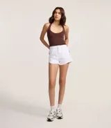 Short de sarga color blanco, modelo slim, con trabillas en la cintura, bolsillos, cierre delantero con botón y cremallera, y terminación deshilachada.