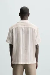 Camisa de hombre a rayas verticales color beige y blanco, de corte relaxed fit, manga corta y cuello bowling.