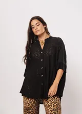 Camisa negra con calados, escote en V, abotonada y manga 3/4.