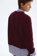 Cárdigan corto de punto acanalado en color vino tinto, con cuello redondo, cierre frontal de botones dorados y bolsillos de parche con botón en la parte delantera.