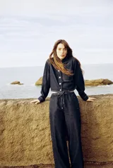Pantalón de jean azul oscuro, de tiro medio, corte ancho y largo, estilo jogger con cintura elástica ajustable con cordones, bolsillos delanteros de vivo y bolsillos de parche en la espalda.