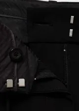 Pantalón negro de vestir, de corte recto y largo, con tiro medio, trabillas, bolsillos laterales y cierre frontal oculto con botón, gancho y cremallera. Incluye lazo ajustable en la cintura y forro interior.