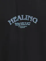 Remera negra de manga corta con cuello redondo y estampado azul con la palabra "healing" en el pecho.