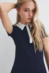 Vestido corto azul marino con cuello blanco, tapeta de botones y pollera acampanada.