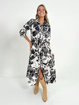 Vestido camisero midi con estampado floral en blanco y negro, manga 3/4, botones al frente, falda de estilo campesino y cinto incluido.