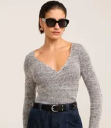 Blusa negra de punto acanalado, con escote en V profundo y mangas largas.
