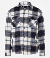 Campera trucker masculina de franela a cuadros en tonos blanco, negro y gris, con cuello inglés, abotonado delantero, bolsillos con solapa en el pecho y bolsillos laterales. Interior forrado en sherpa.