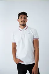 Remera cuello polo blanca de piqué, corte regular, manga corta, logo estampado y terminaciones a contratono en cuello y mangas con rayas rojas, grises y azules.