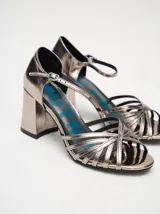 Sandalias negras de charol con tiras cruzadas en el empeine, pulsera con hebilla al tobillo y tacón cuadrado.