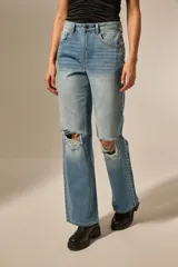 Pantalón jean negro con roturas en las rodillas, diseño de estrellas metálicas a lo largo de las costuras laterales y en los bolsillos delanteros.