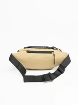 Riñonera color beige con detalles en negro, con tres compartimentos con cierre y correa ajustable con hebilla.