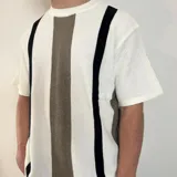 Remera de punto calado color blanco con rayas verticales marrones y negras, corte holgado y mangas cortas.