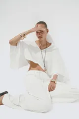 Pantalón blanco de lino, de corte ancho, tiro medio, con trabillas y cintura elástica ajustable con cordones.