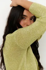 Sweater de tejido de punto fino con brillo metálico, color verde lima. Presenta escote en V y mangas largas.