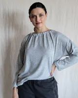 Remera gris de cuello redondo con frunce y mangas largas.