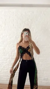 Top corto con estampado animal print en tonos verde y negro, con detalles de encaje negro en el escote y ruedo.