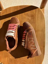 Championes urbanos de cuero color blanco hueso con detalles en marrón. Presentan cordones de algodón color crudo y logo bordado en el lateral.