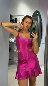 Minivestido fucsia de lurex con un solo tirante, corte en la cintura y falda con volantes.
