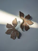 Aros grandes con forma de flor color bronce con glitter y borde de strass. Cierre a presión de acero inoxidable.