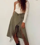 Pollera midi de cuero color verde oliva, con corte irregular, detalle de flecos en el ruedo y cierre con botón a presión.