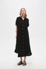 Vestido camisero midi negro de corte holgado, con cuello camisero, mangas cortas con trabillas, cierre frontal con botones, bolsillo en el pecho y bolsillos laterales.