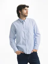 Camisa celeste y blanca a cuadros con cuello abotonado, manga larga y bolsillo en el pecho.