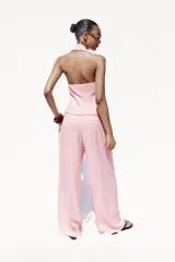 Pantalón ancho color rosa claro, de tiro alto con pinzas delanteras, bolsillos frontales y cierre frontal con cremallera y botones.