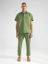 Pantalón largo verde oliva de algodón con textura seersucker, corte recto, bolsillos laterales y traseros, cierre con botón y cremallera.