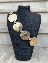 Cinto dorado de metal con eslabones y monedas circulares texturadas.