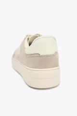 Zapatillas deportivas color beige, estilo soft, con cuerpo en combinación de materiales y cierre mediante cordones. Suela de 3 cm de altura.