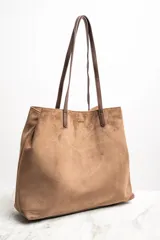 Bolso tipo tote de gamuza vegana color camel, con asas de mano y logo grabado en el frente.