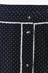 Falda midi azul marino con estampado de lunares blancos, tiro alto, bolsillos laterales ocultos, detalle de vivo blanco a contraste y cierre frontal con botones.