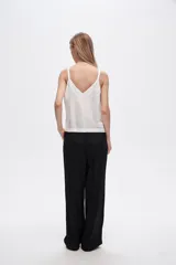 Pantalón negro de rayon, corte amplio, tiro alto y bolsillos laterales.