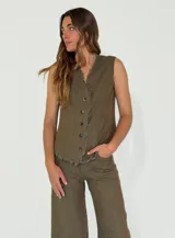 Chaleco beige de lino con escote en V, cierre frontal con botones y terminaciones desflecadas.