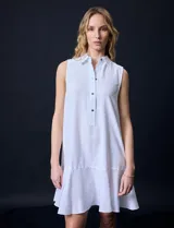 Vestido corto blanco de gasa, sin mangas, con cuello camisero, abertura central con botones y terminación de ruedo con volado.