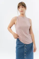 Musculosa color rosa metalizado, sin mangas, confeccionada en lino metalizado, con escote cerrado al frente y espalda abierta con lazo ajustable.