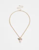 Collar corto dorado con cadena de eslabones gruesos y dijes colgantes: cristal facetado azul, dije dorado con forma de abanico, dije ovalado blanco con corazón dorado y strass, perla rosa y perla blanca.