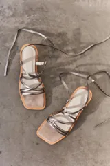 Sandalias plateadas con tiras finas cruzadas y tobilleras con cordones. Tacón de madera.