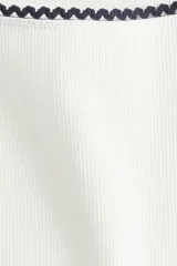 Top blanco de punto acanalado con mangas largas y escote cuadrado con ribete de picot.