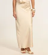 Vestido largo de satén color crema, con escote halter, espalda descubierta y abertura frontal. Presenta detalles de pedrería en el escote.